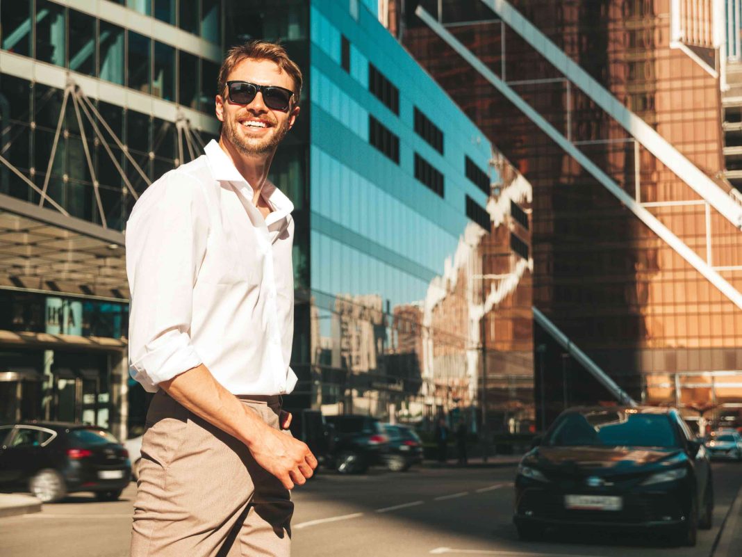 Portrait of handsome smiling stylish hipster lambersexual model.Modern man dressed in white shirt. Fashion male posing in the street background near skyscrapers in sunglasses Tips for the Modern Man in Fashion, Grooming, and Lifestyle