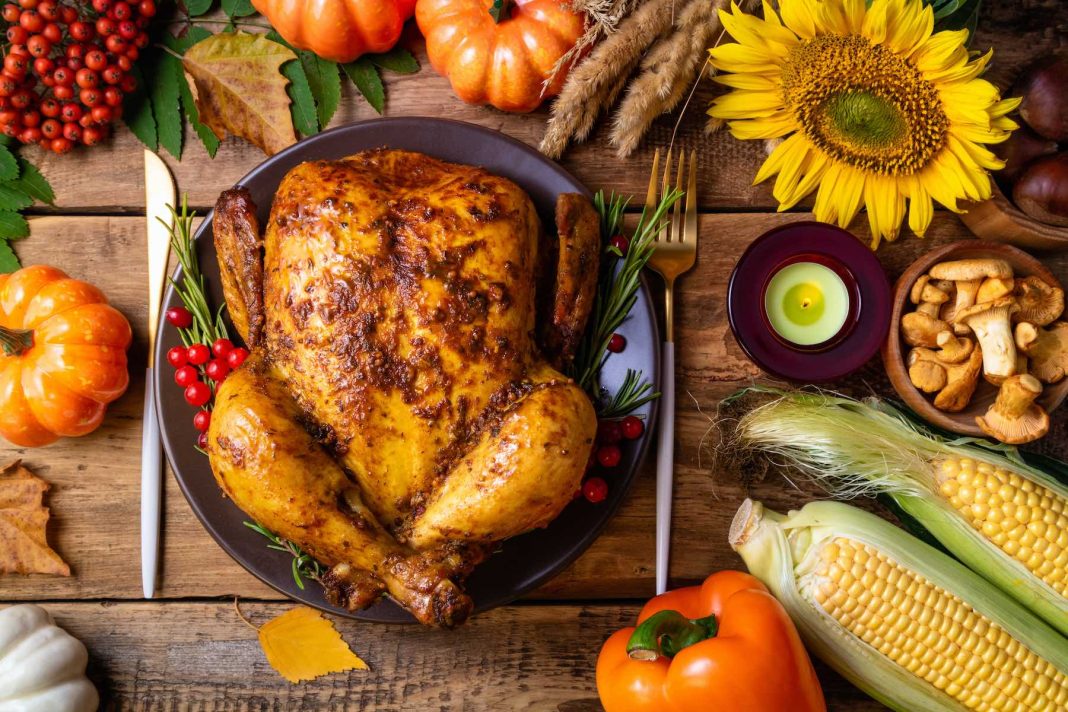 Baked chicken for Thanksgiving Day. Roasted whole chicken or turkey with autumnal vegetables, mushrooms and berries for thanksgiving dinner on wooden table. Thanksgiving Day concept. Top view, copy space Best Roasted Turkey Recipe for This Thanksgiving