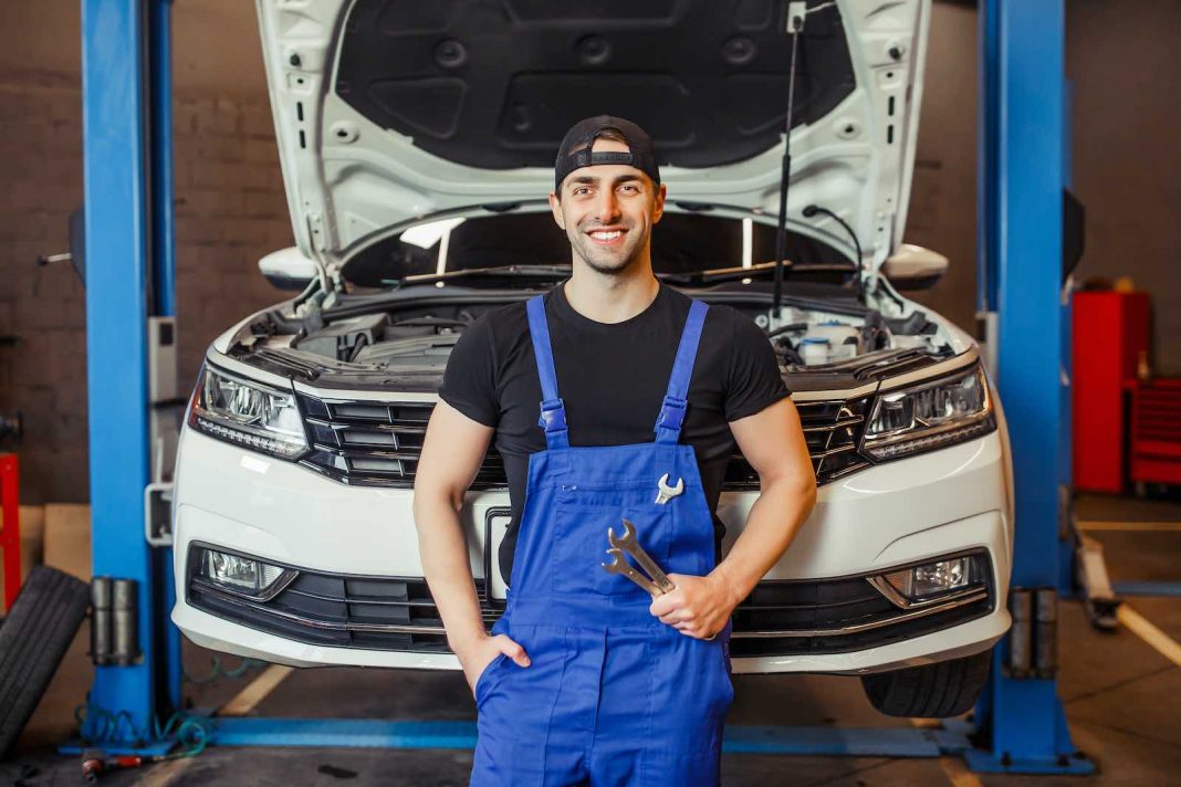 mechanic man in uniform holding wrenches in the auto service center and smiling at the camera Clean, Maintain, and Modify Intake Manifolds